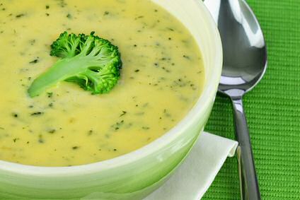 Bloemkool en broccoli geroosterd in de oven, gepureerd met gekarameliseerde uien en bouillon, geserveerd in een kom met bovenop een broccoliroosje